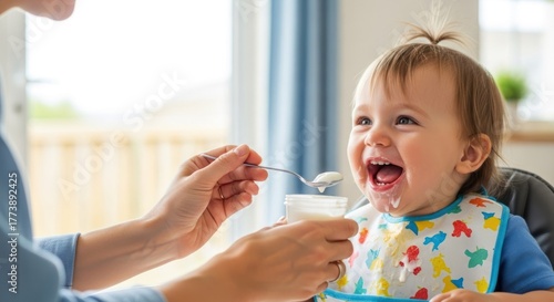 A baby eating yogurt from a spoon.