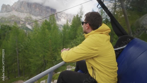 Traveler man wearing a yellow jacket riding a cable car near the Cinque Torri in the Dolomites, Italy.Travel adventure in the Alps and Dolomites surrounded by mountains