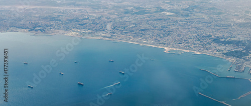 Aerial view of the Algiers city bay with ships on the Mediterranean sea and the capital city coast with the commercial dock piers, the Algeria great mosque, buildings and the Oued El Harrach river.