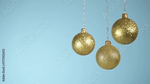 Golden Christmas balls swinging and blurs on a blue background.
