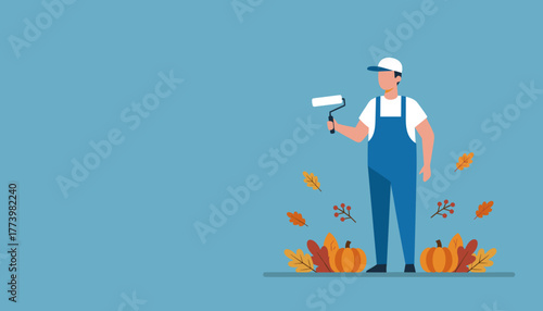 Professional painter in overalls holding a roller standing among pumpkins and autumn leaves