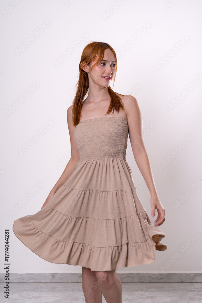 Naklejka premium red haired woman posing playfully and smiling in front of white background confident and natural studio portrait