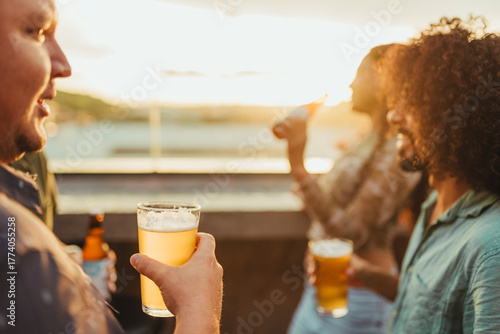 Group of Latino friends enjoying cold beers at a rooftop bar during sunset. The scene captures the joy and warmth of socializing outdoors, with a golden light ambiance and relaxed summer vibes.