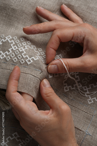 Close-up of a natural-colored linen shirt, hands embroidering traditional Ukrainian embroidery. Embroidery on a shirt