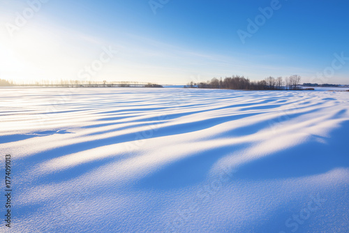 Fresh snowdrift ripples on an open field at sunrise, long blue shadows, minimal horizon line, serene landscape, room for headlines