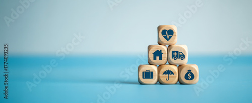 Wooden blocks with insurance icons stacked in a pyramid representing protection and security for financial planning and risk management concepts