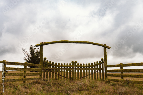 Portera de madera cubierta de musgo, de entrada a una estancia de campo.