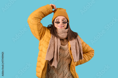 Young woman in winter clothes on blue background
