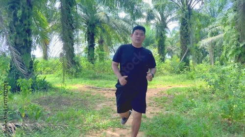 Man running on dirt trail surrounded by palm trees