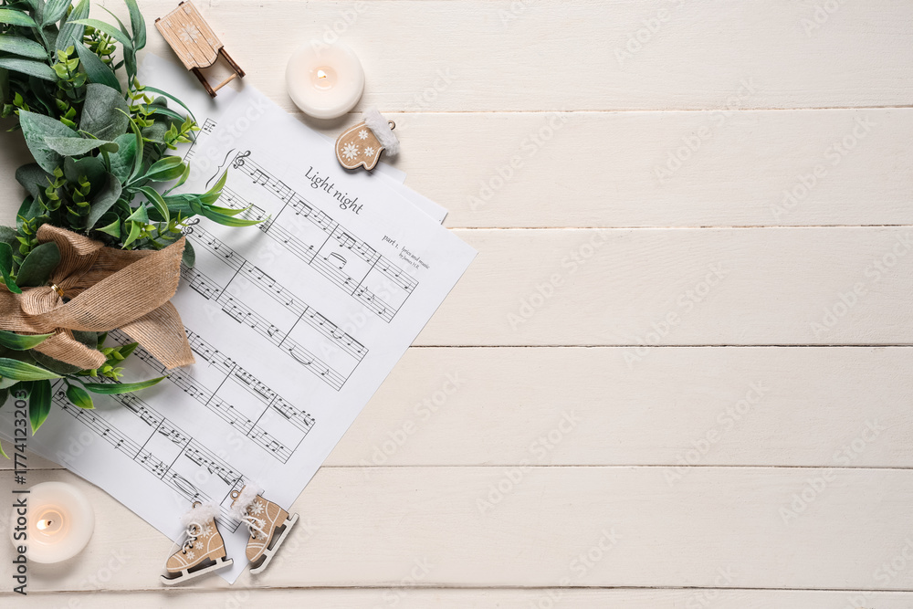 Obraz premium Composition with music sheets, burning candles and Christmas decorations on white wooden background
