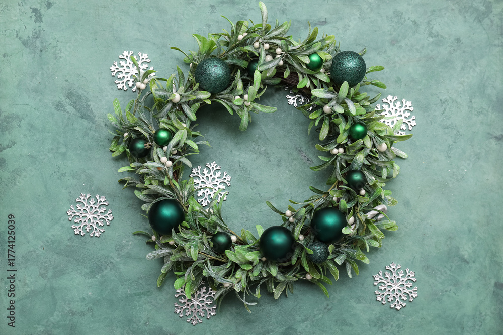 Obraz premium Christmas mistletoe wreath with beautiful decorations and snowflakes on grunge green background