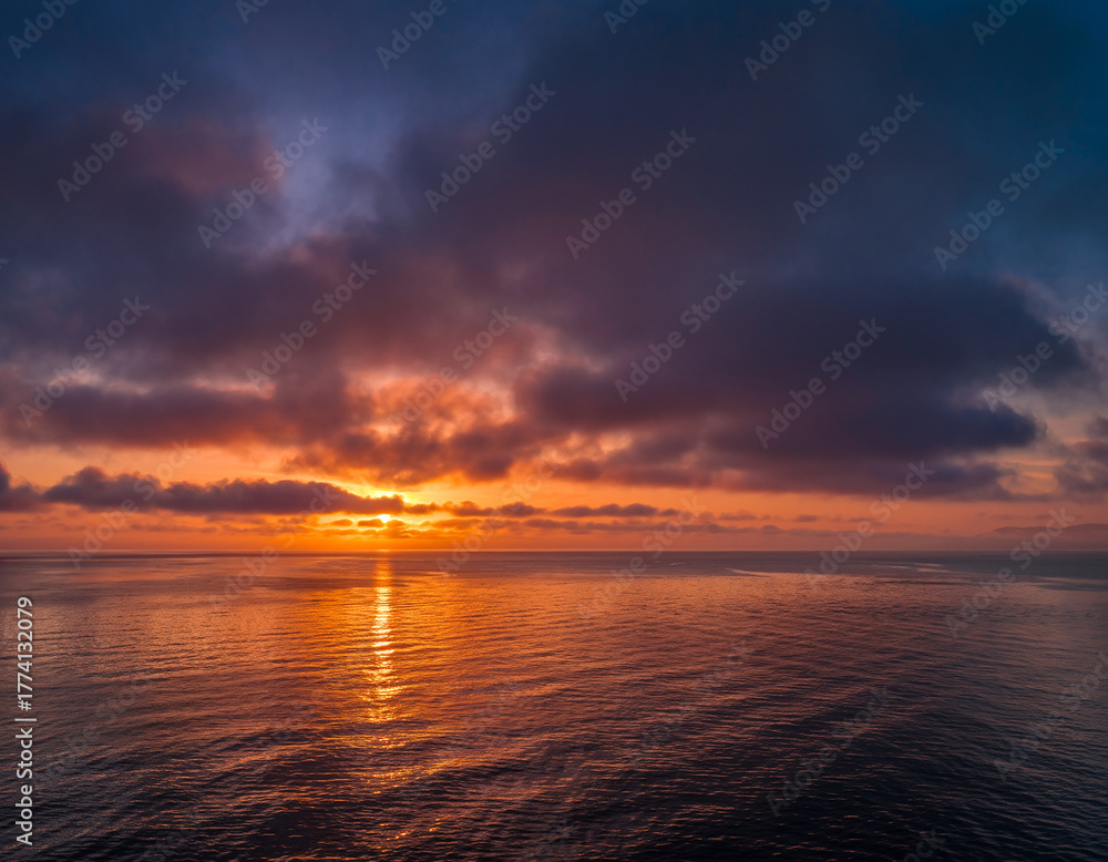 Naklejka premium Dramatic colorful sunset over the calm ocean water.
