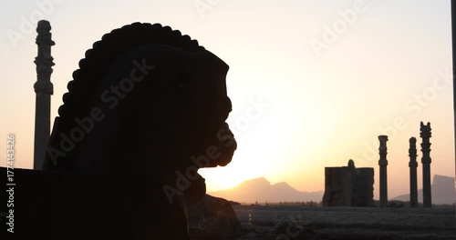 Silhouetted winged bull capital and ancient columns of Persepolis at sunset as the sun drops behind the Zagros. A quiet frame of heritage, empire and endurance across Iran’s desert horizon.