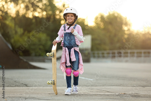 Cute little girl with skateboarding gear in park