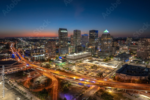 Tampa city in Florida with brightly illuminated highway traffic and skyscraper buildings in downtown district. American megapolis with business financial district at night.