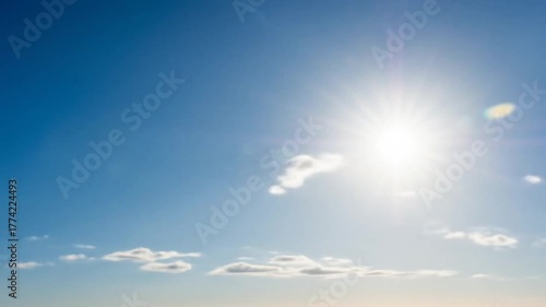Bright sun shining in a clear blue sky with scattered clouds