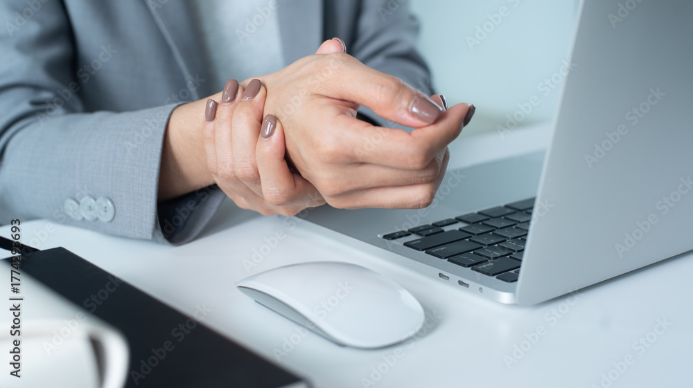 Fototapeta premium Closeup business woman holding her wrist pain from using computer. Office syndrome hand pain by occupational disease.