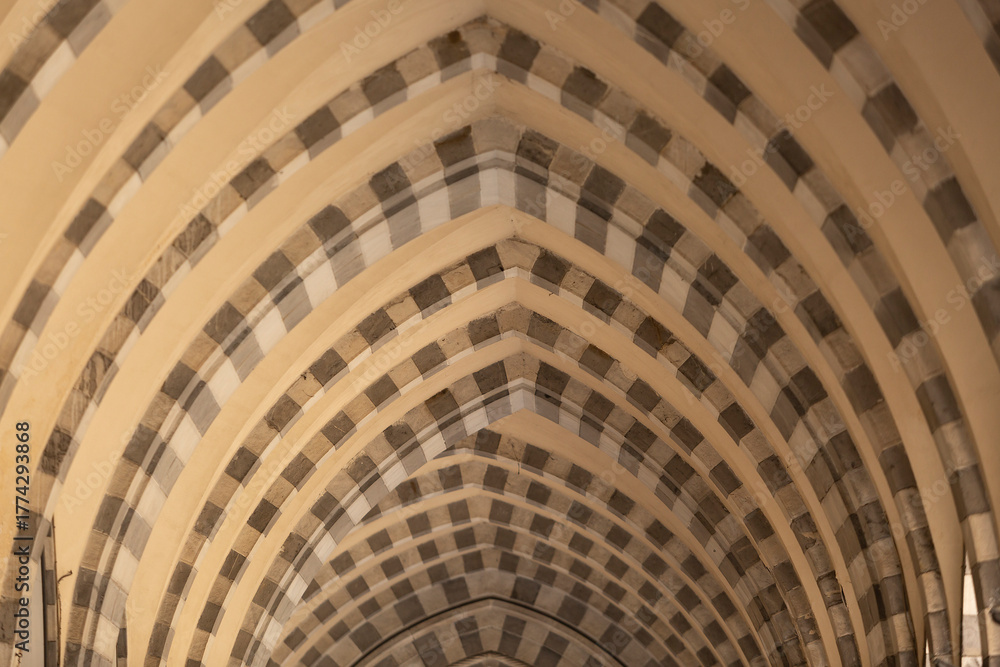 Fototapeta premium Looking through repetitive arches with pattern of dark and light coloured stones, Genoa