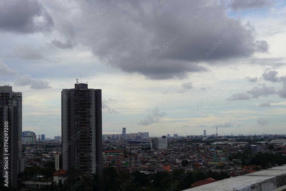 Fototapeta premium Brooding Storm Clouds Gather Over a Sprawling Dense Jakarta Cityscape.