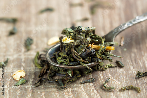green tea leaves in a spoon on wooden background. a sample for package design