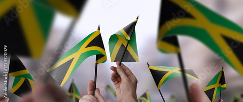 Jamaica flags in their hands on a blurred urban background
