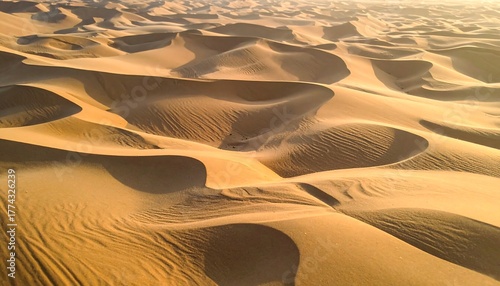 Fototapeta Naklejka Na Ścianę i Meble -  Aerial view of vast, undulating sand dunes under warm sunlight