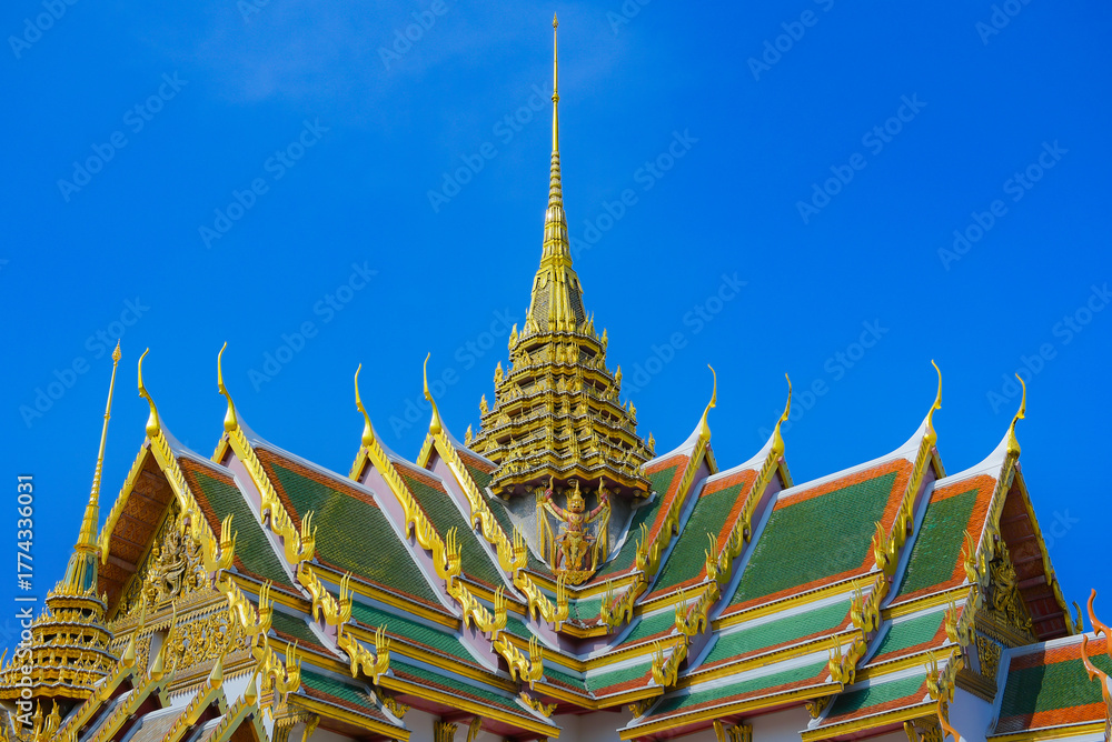 Fototapeta premium The ornate rooftop of Dusit Maha Prasat Throne Hall in the Grand Palace, beautifully designed with intricate architectural details, showcasing the elegance of traditional Thai royal architecture.