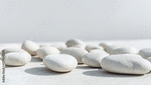 smooth white pebbles evenly spread on light gray surface, soft daylight, minimal spa composition background