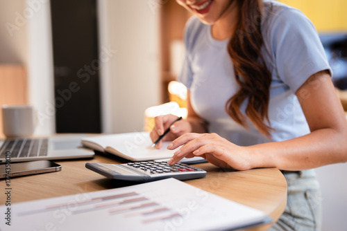 Deduction planning, debt asian young woman  hand using calculator to calculating  money balance from bill and income, cost budget expenses for pay money form personal individual on table at home.