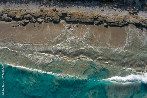 Waves wash toward a rocky shore in the clear blue waters around Esperance