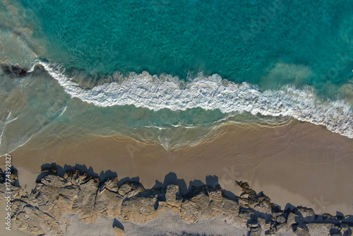Turquoise waves lap the golden sand as they wash over the beach 