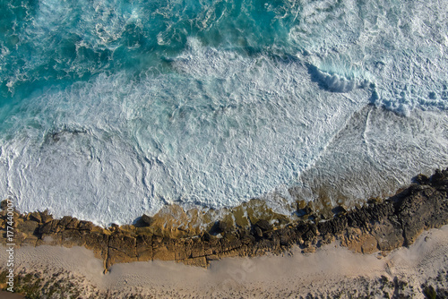Waves break into a white surf foam as they pound the shore