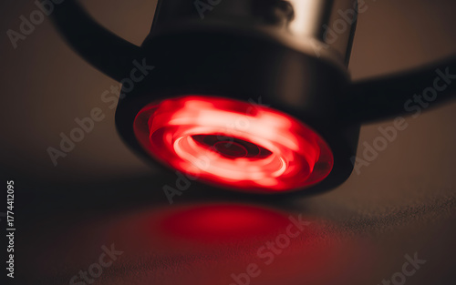 Closeup of a red glowing light source within a dark metallic object