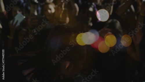 Singer stepping on concert stage starting singing into mic as phone lights energizing crowd