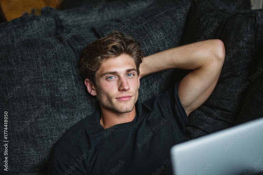 Obraz premium Young man lounging on a couch with a laptop