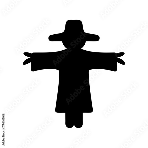 A silhouette of a scarecrow with a hat and arms outstretched in the field