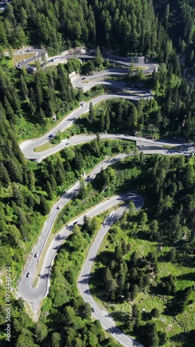 Drone view of winding Maloja Pass road in Swiss Alps with serpentine turns among mountains and forests showing travel adventure and beautiful alpine landscape