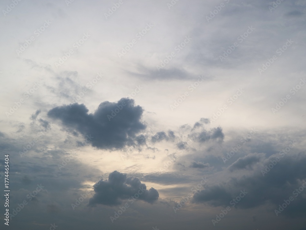 Obraz premium Dark, moody storm clouds are gathering in a dramatic sky with a pale, faintly lit opening near the center, suggesting impending rain or a stormy atmosphere