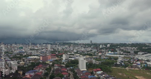 Zoomed out shot of Sihanoukville's diverse, hilly cityscape under a heavy, looming storm cloud.