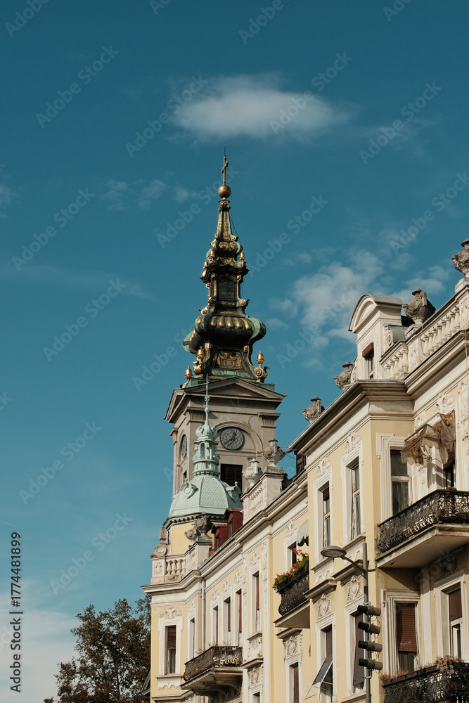 Fototapeta premium Golden church tower and ornate building facade under blue sky in old Belgrade, Serbia