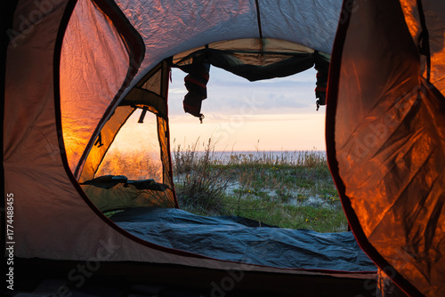 Fototapeta Naklejka Na Ścianę i Meble -  Scenic view from inside an open tent overlooking the Baltic Sea coast at sunrise during a wild camping trip in Estonia.