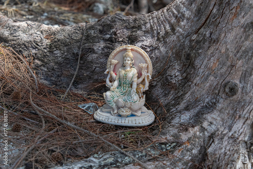 Kleine Hindufigur an einer Baumwurzel versteckt