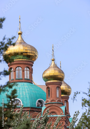 golden domes of a Christian brick church with a cross
