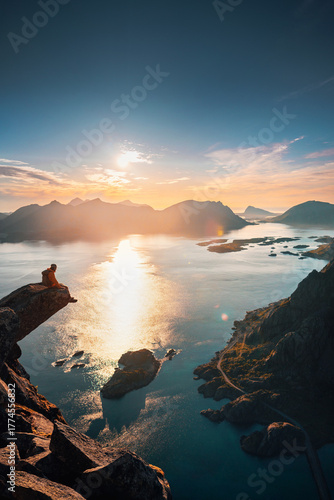 Epic travel in Lofoten islands - man sitting on Torsketunga cliff edge above sea climbing mountains solo in Norway, active extreme adventure tour summer holidays outdoor freedom sunset landscape view
