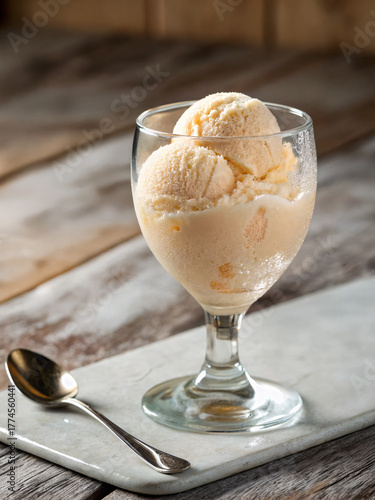 Deliciously creamy peach ice cream served in a clear glass with a golden spoon on the side