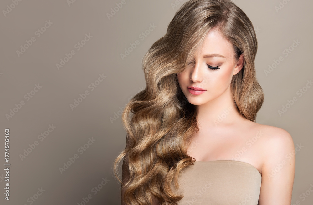 Naklejka premium Blonde girl with long and shiny wavy hair . Beautiful model woman with curly hairstyle . Beauty and cosmetology 