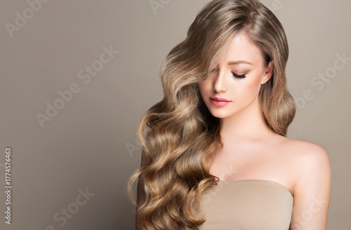 Blonde girl with long and shiny wavy hair . Beautiful model woman with curly hairstyle . Beauty and cosmetology

