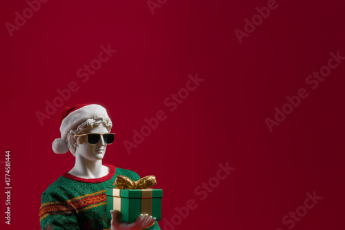 A statue of a Greek god holding a gift box. A man in a knitted sweater holding a Christmas present.