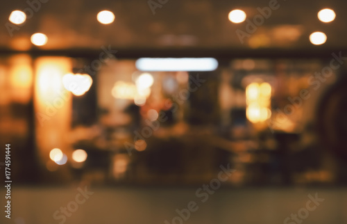 Defocused view of modern cafe or restaurant interior with warm golden bokeh lights abstract background at night