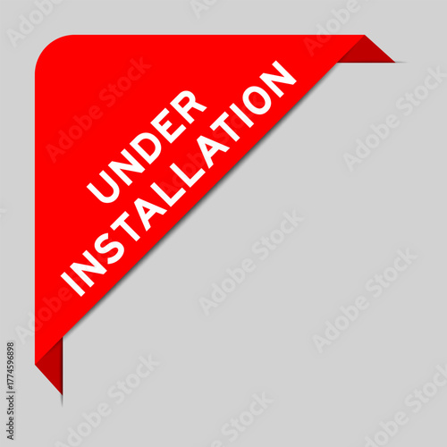 Red color of corner label banner with word under installation on gray background